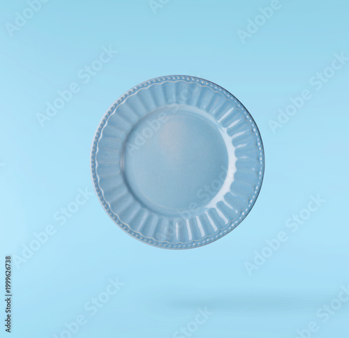 Canvas Print Levitating empty ceramic plate isolated on a pastel blue background