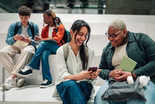 Obraz na plátně Diverse university students connecting and sharing content on mobile phones in a