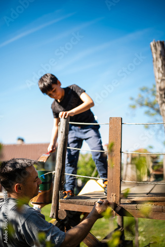 фотографія Father and son painting wooden treehouse together