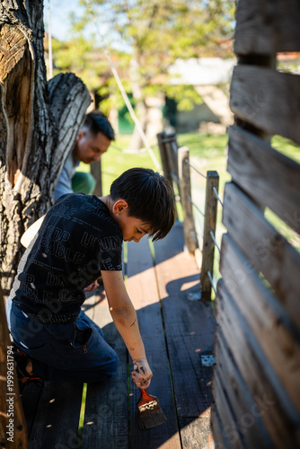 Quadro su tela Boy and father painting wood treehouse outdoors