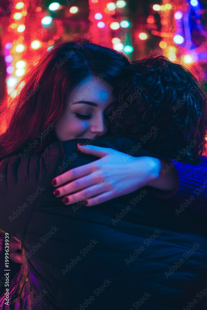 Naklejka premium A pair embracing in front of a decorated Christmas tree vertical frame