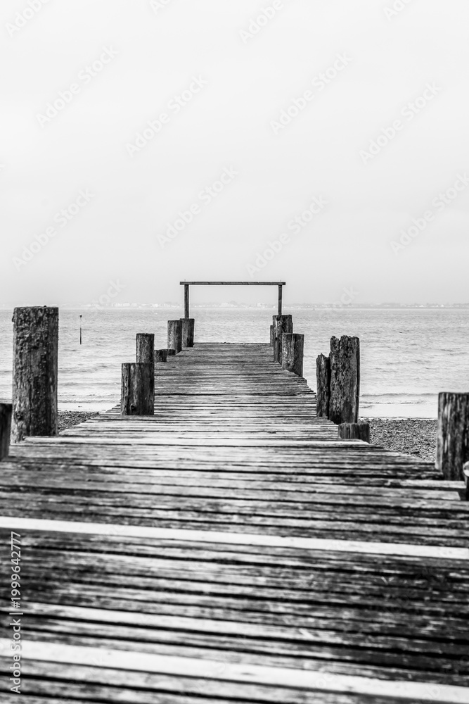 Fototapeta premium A black and white photograph of a wooden pier on Player's Beach on the Isle of Wight