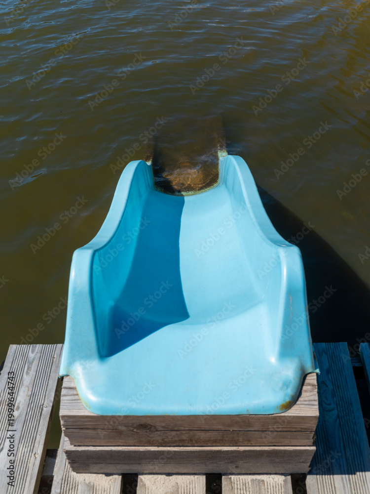 Fototapeta premium A plastic slide mounted on a pier over the lake leading straight into the water.