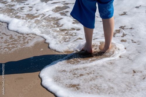 Cuadro en lienzo A refreshing wave of sea foam surrounds a person's feet on a sunny beach, captured in sharp detail