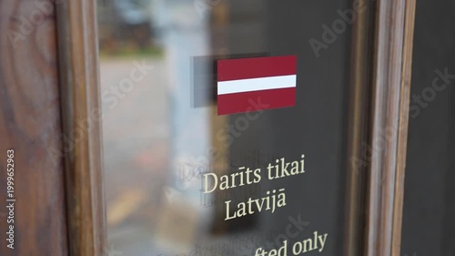 Handcrafted sign with Latvian flag displayed on a wooden door, showcasing the craftsmanship and cultural identity of Latvia