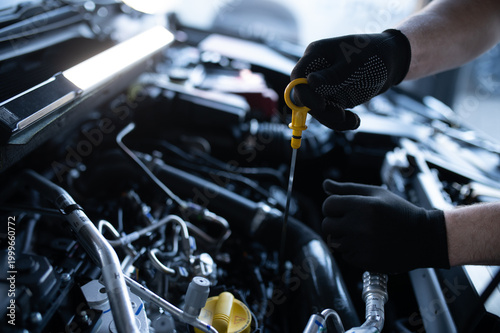 фотографія Mechanic checking car engine oil level with dipstick