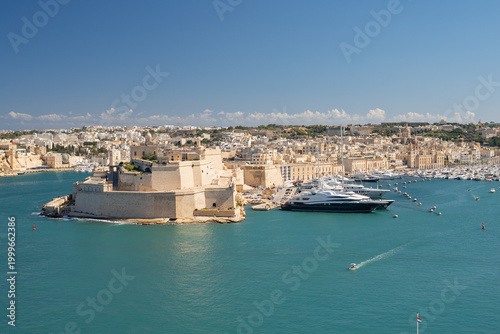 Horizontal panoramic view of Fort St. Angelo and luxury yachts in the Grand Harbour. Historic architecture of Birgu, Malta.