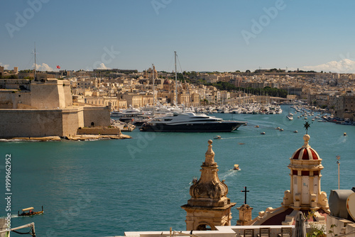 Horizontal panoramic view of the Grand Harbour with luxury yachts and Fort St. Angelo. Historic cityscape of Valletta and Birgu, Malta.
