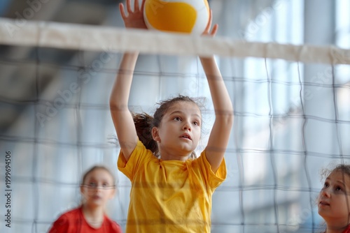 Young girl serves volleyball during indoor game practice