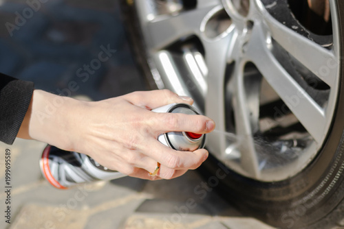 Fotografía Hand of a person applying tire shine spray to a car wheel, showcasing the shiny