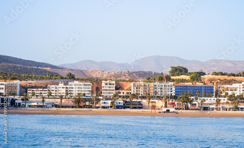 Seaside view of Agadir, Morocco. Agadir beach, cable car, shops and restaurants near Corniche promenade. Popular tourist resort on Atlantic ocean coast near Atlas Mountains in West Africa