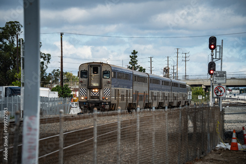 Konstfotografi Amtrak train traveling on tracks with a cloudy sky overhead