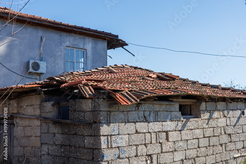 Damaged clay tile roof on a weathered stone outbuilding