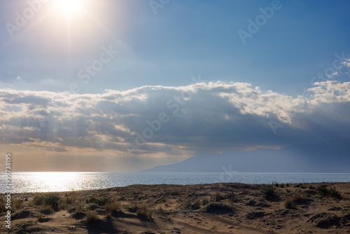 Sunlit sandy beach by the sea at golden sunset