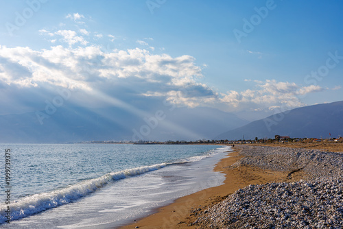 Sunlit pebble beach with waves at golden hour