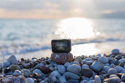 Action camera on pebbled beach at sunset