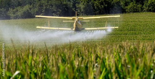 Yellow Crop Duster Sprays Fields Beneath Clear Sky