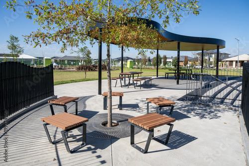 Bild auf Leinwand Contemporary public outdoor seating area in a newly developed suburban park in Australia, featuring seats arranged around a young shade tree