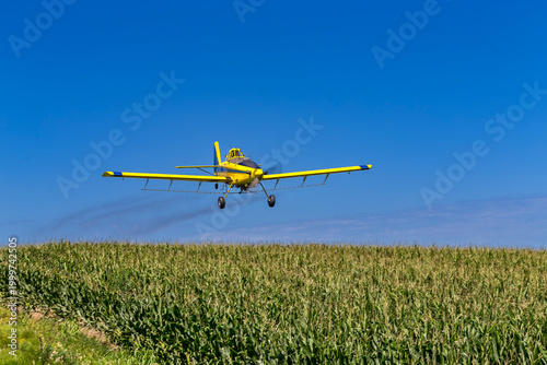 Yellow Crop Duster Sprays Fields Beneath Clear Sky