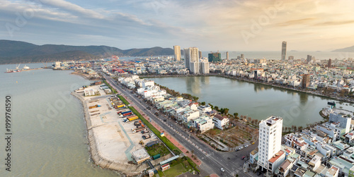 Cuadro en lienzo Aerial view of Sinh Thai Lake, Quy Nhon, Binh Dinh, Vietnam, showing the port with shipping containers and trucks, and the city skyline with modern buildings and mountains in the background