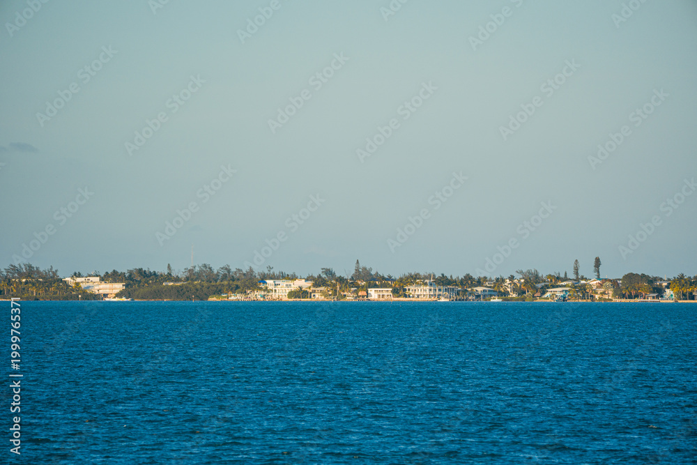 Fototapeta premium Coastal residential houses and green trees along the blue Atlantic Ocean water in the Florida Keys islands, USA.