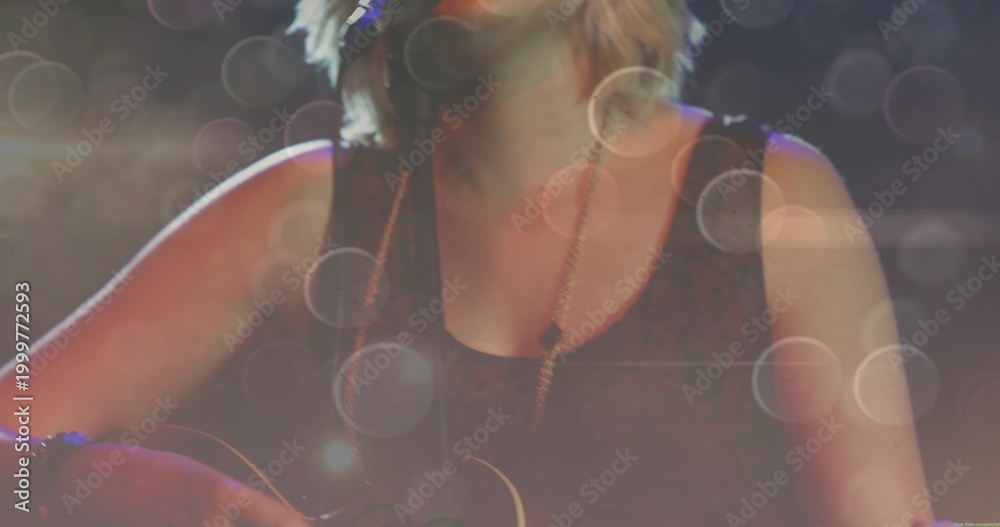 Fototapeta premium Singing teen performer playing guitar into mic onstage wearing sleeveless black top and necklace
