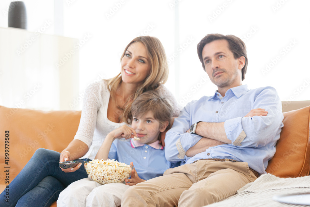 Fototapeta premium A happy family is sitting on the couch watching TV