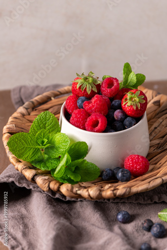 Fresh Mixed Berries in a Ceramic Bowl with Mint on a Rustic Woven Plate
