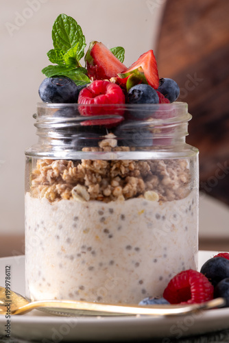 Layered Chia Seed Pudding and Granola Parfait with Fresh Berries in a Glass Jar