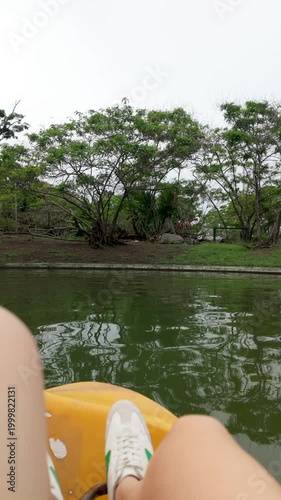 First person view of legs using paddle boat at lake city - Travel summer vacation concept - Vertical video