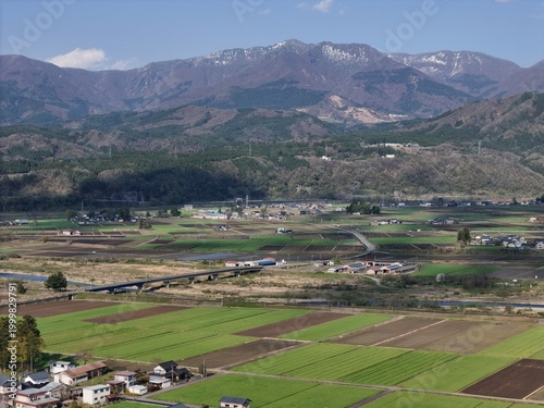 Vibrant green fields stretch beneath distant snow-capped peaks