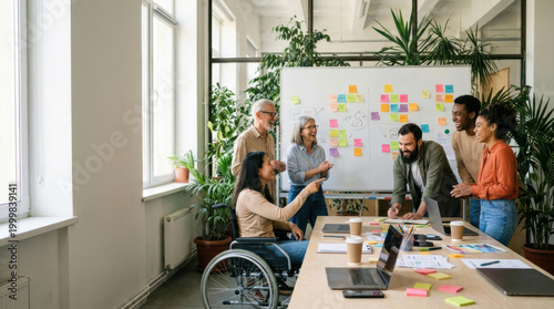 Diverse team meeting creative office startup workspace business collaboration wheelchair user inclusive workplace brainstorming session planning strategy sticky note wall happy colleagues