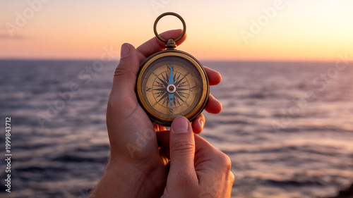 Hand holding vintage compass at golden hour by the ocean