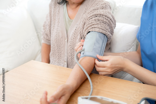 Asian woman nurse measuring blood pressure senior patient, medical checking for hypertension monitoring, caregiver support elderly woman with arterial blood pressure device, routine health checkup.