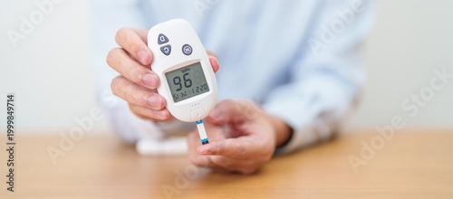 Tableau sur toile Hand checking Diabetes or Blood glucose self testing by digital blood glucose meter with lancet pen
