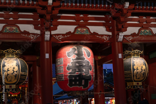 Tourists at Senso-ji temple gate with large lantern at night, Tokyo