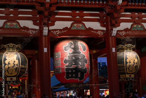 Tourists at Senso-ji temple gate with large lantern at night, Tokyo