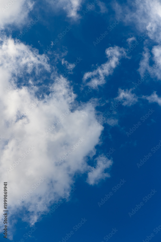 Obraz premium Fluffy white clouds drift gracefully across a bright blue sky on a sunny afternoon