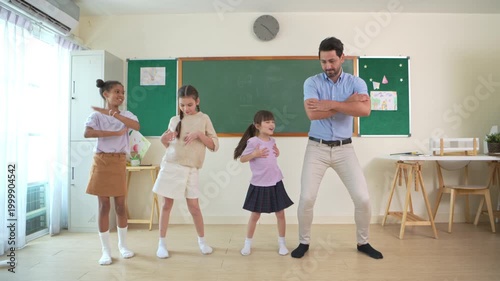 Diverse group of school children enjoying dance activity with teacher in an international classroom, encouraging active learning and teamwork