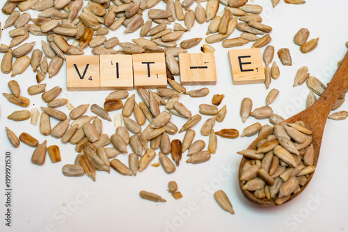 Sunflower seeds with spoon and alphabet blocks spelling vitamin E on white background
