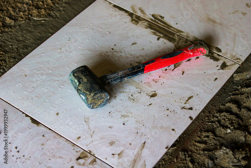 Black rubber mallet hammer on ceramic tile surface at construction site