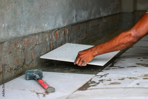 Tiler placing ceramic tile on wet mortar during home renovation