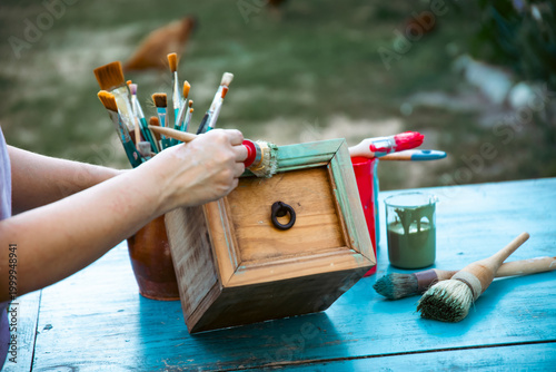 Painting a wooden furniture outdoors, an eco-friendly re-use business.