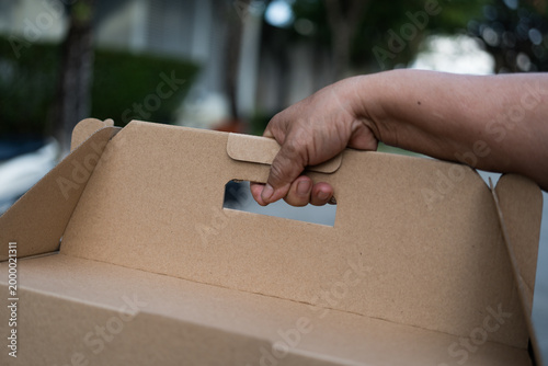 Blank brown cardboard box mockup with handle for food gift packaging in hand