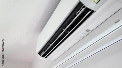 Professional technician using a yellow electric blower to dry the internal components of a wall-mounted air conditioner after a deep cleaning service.