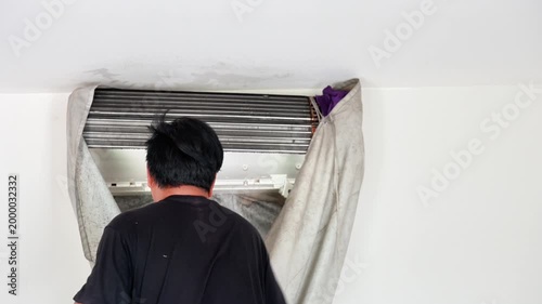 Professional technician using a high-pressure water spray to deep clean an air conditioner's evaporator coils with a protective water-catch cover.