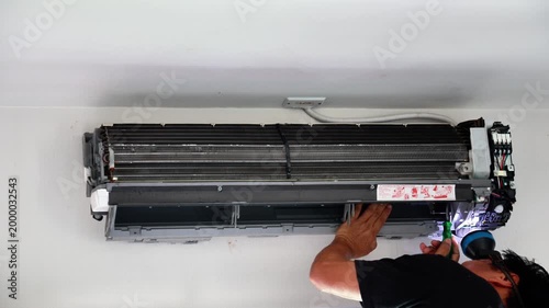Professional technician disassembling and carefully reassembling a wall-mounted air conditioner blower fan during a deep cleaning and maintenance service.