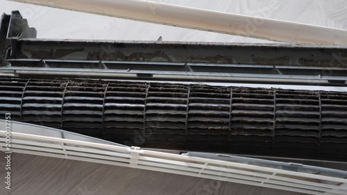 Extreme close-up of a very dirty air conditioner blower wheel and drain pan covered in thick dust, grime, and mold before professional cleaning.