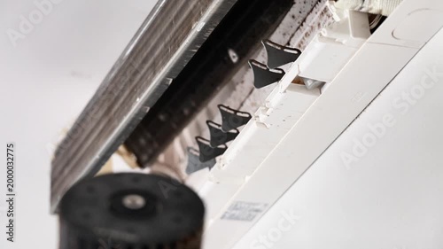 Professional technician removing a very dirty, dusty blower fan wheel from a wall-mounted air conditioner for deep cleaning and maintenance.