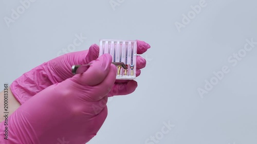 Dentist in Pink Gloves Placing Endodontic File into Organizer with Tweezers
